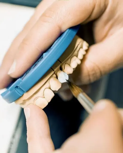 A fine brush shaping tooth-coloured material on a dental model, close up.
